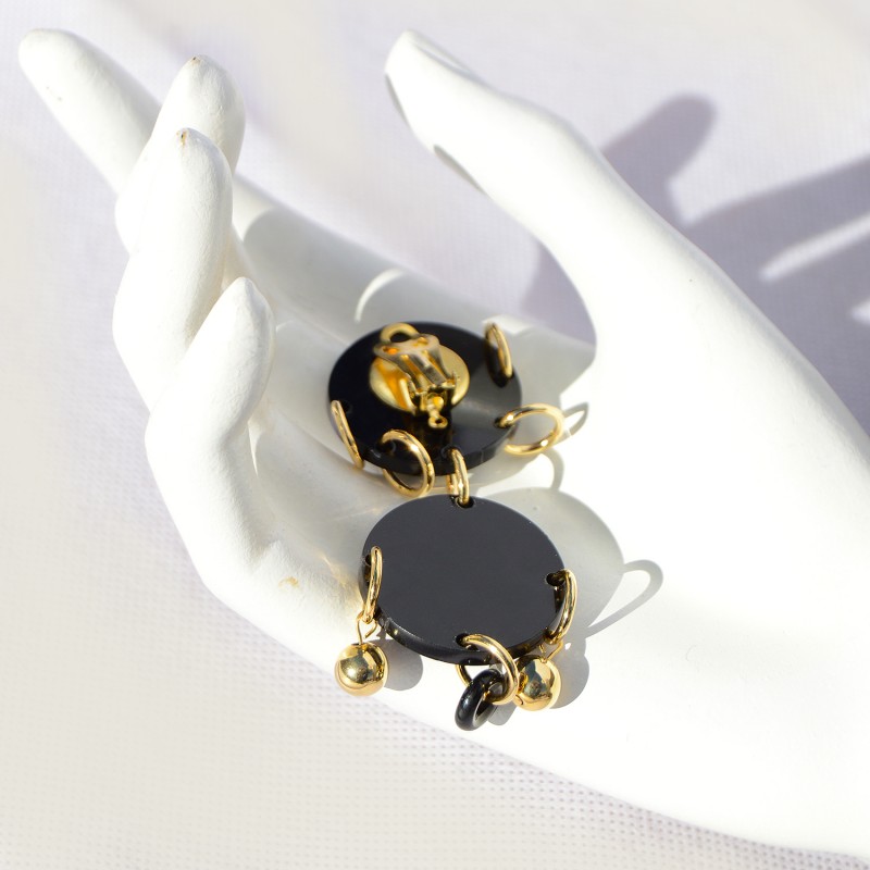 Earrings made in black plexiglass, gold-plated brass, and crystal.